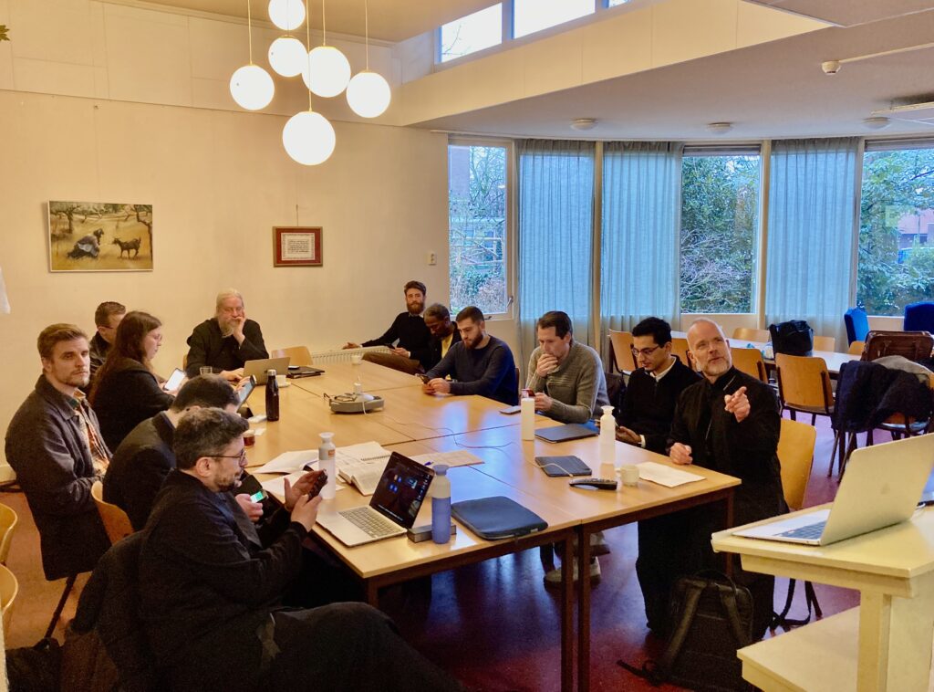 Een groep studenten en docenten gezamenlijk aan tafel